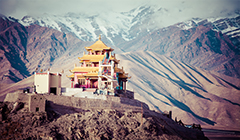 A view of a temple surrounded by snowy mountains in Ladakh
